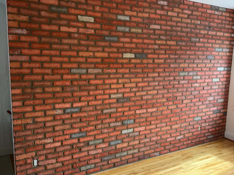 Mur de brique rouge intérieur terminé dans une pièce à plancher de bois